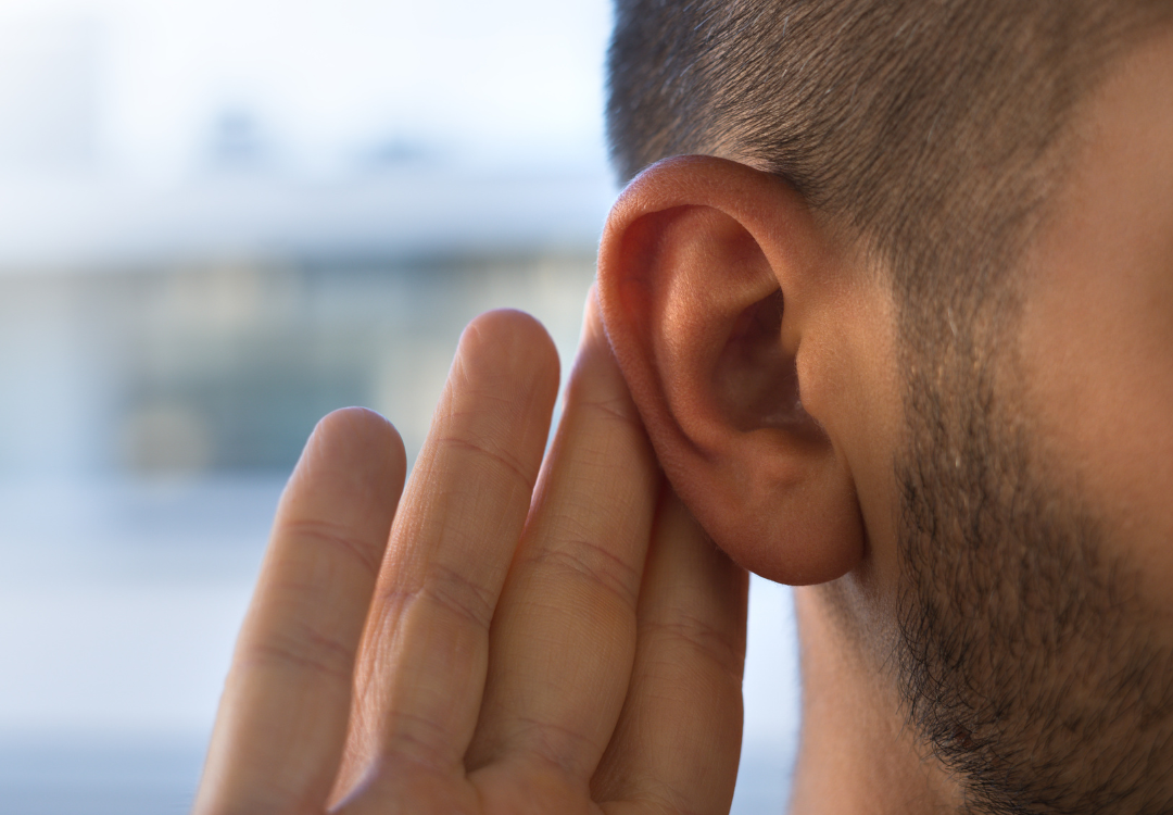 person holding hand up to their ear