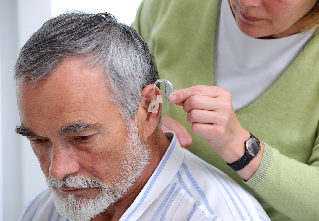 older person getting a hearing aid put in