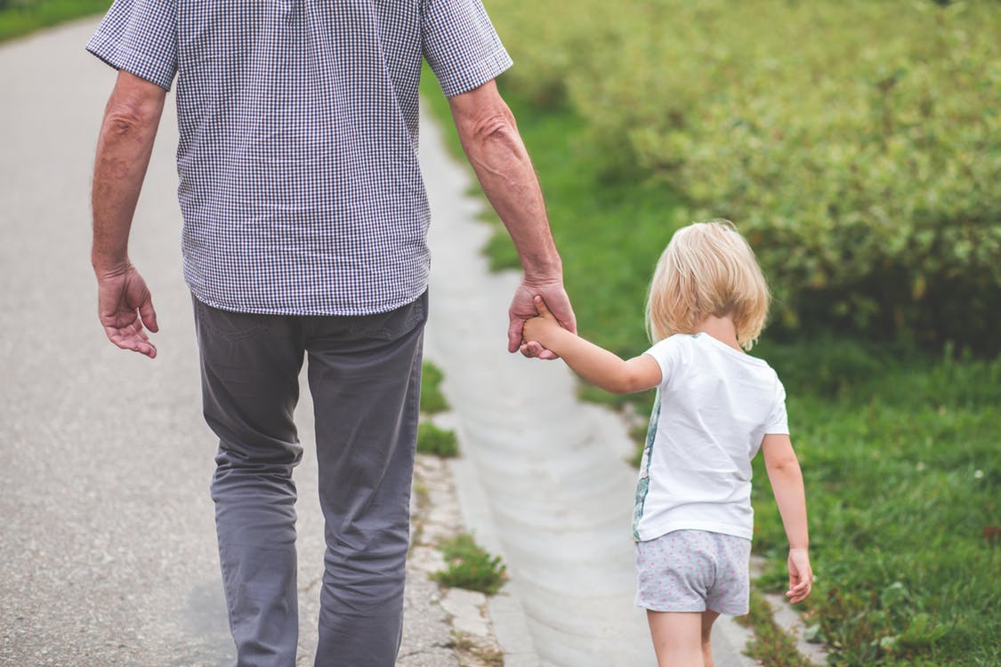 older person holding childs hand while walking