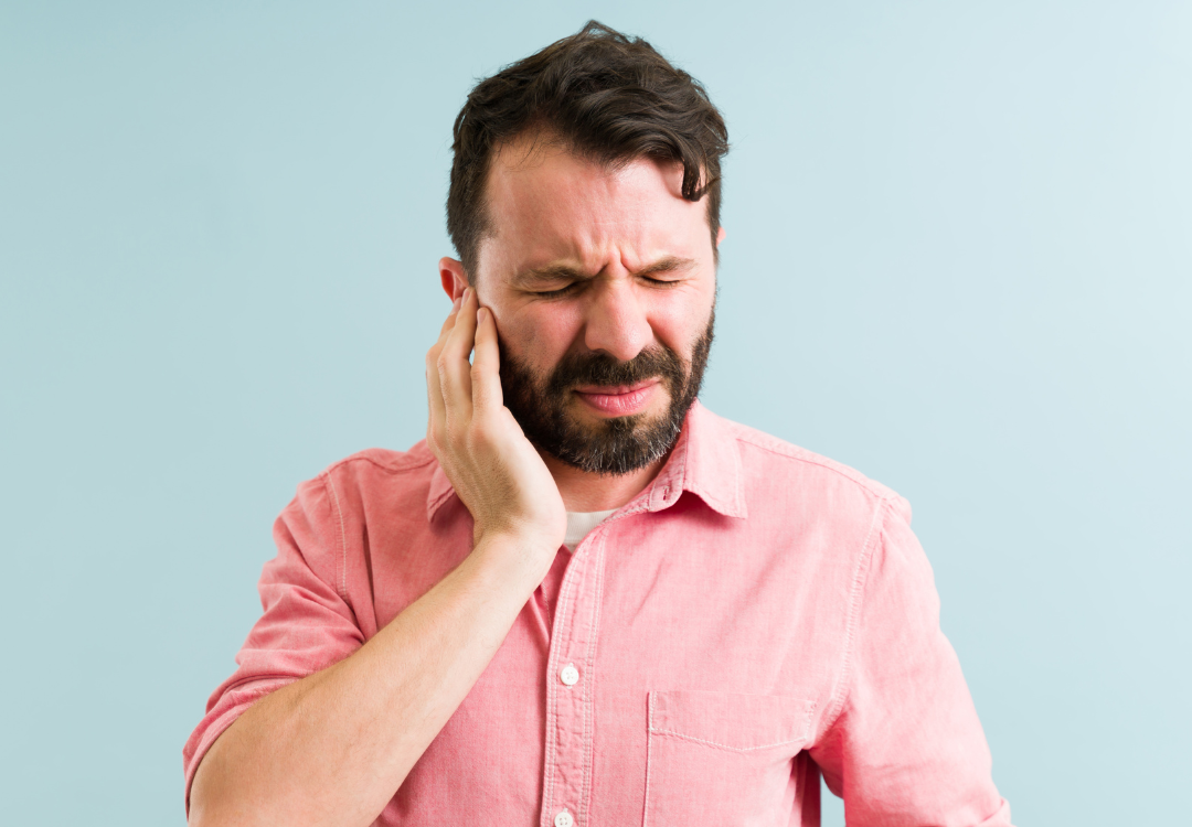 man holding his ear, wincing