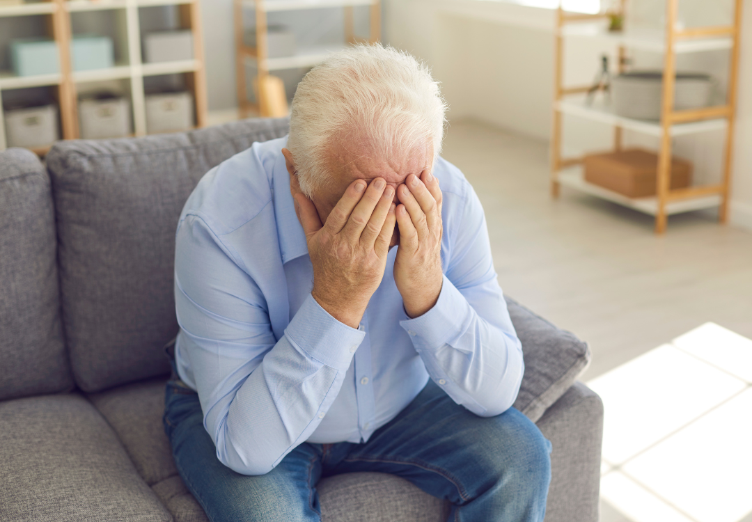 old man with his hands on his face suffering from hearing exhaustion